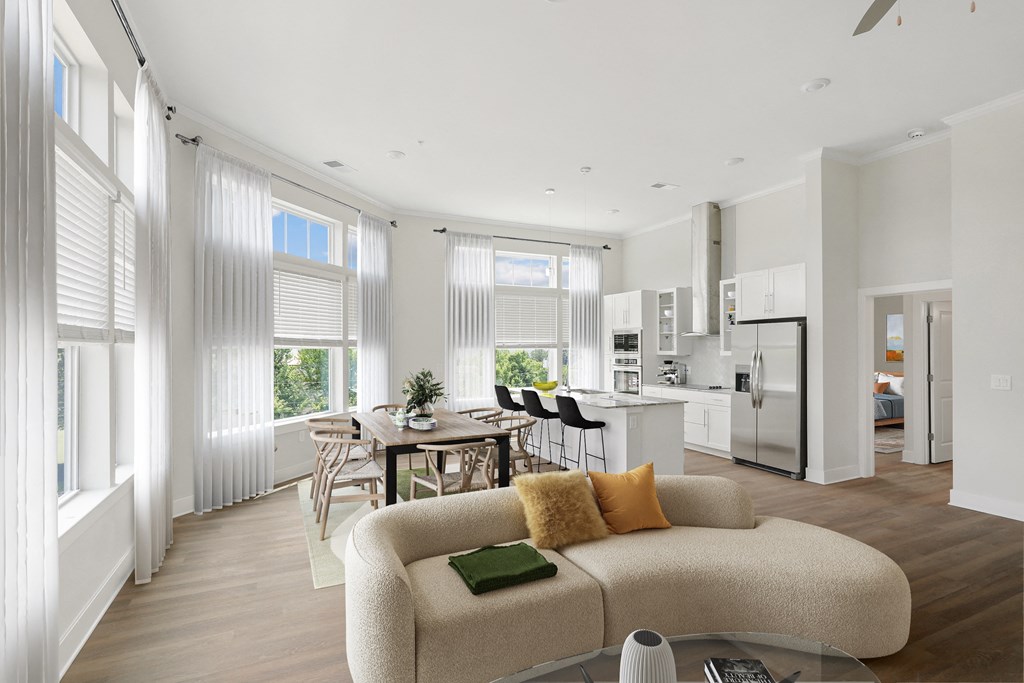 a living room with a couch a table and chairs and a kitchen in the background