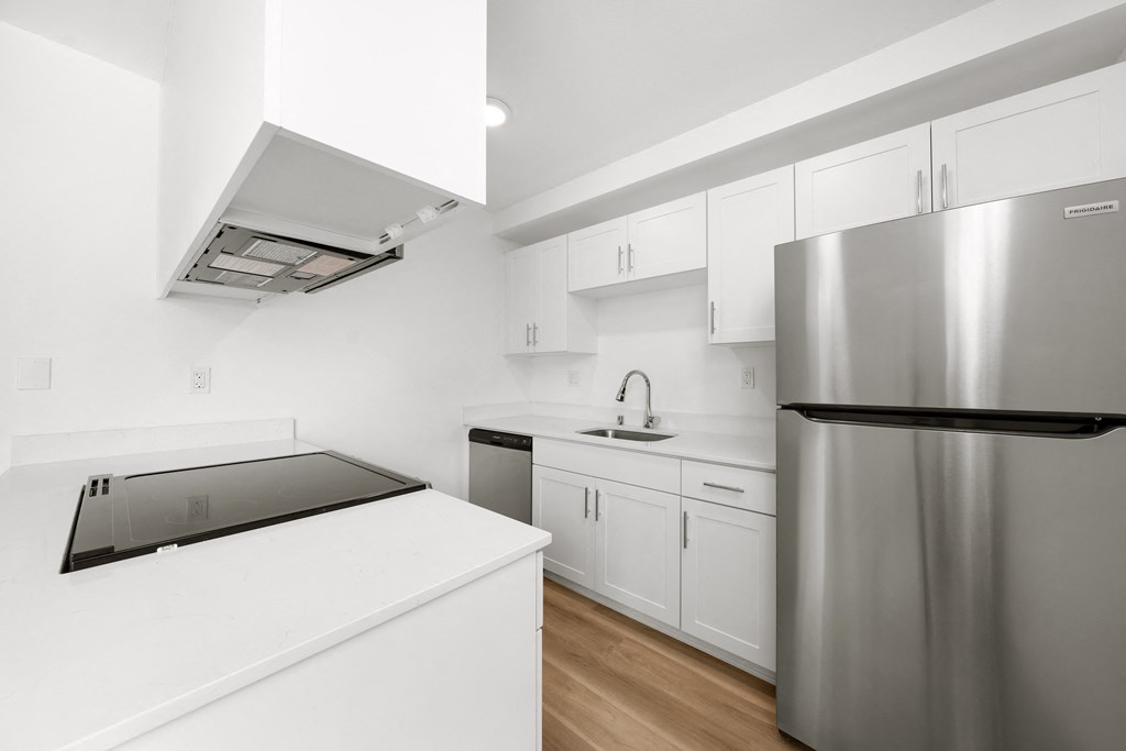 a white kitchen with stainless steel appliances and white counter tops