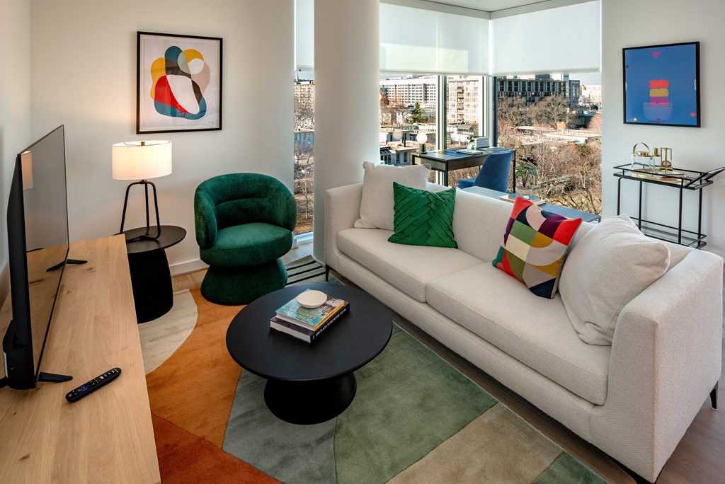 A living room with a white couch, green chair, and a television.