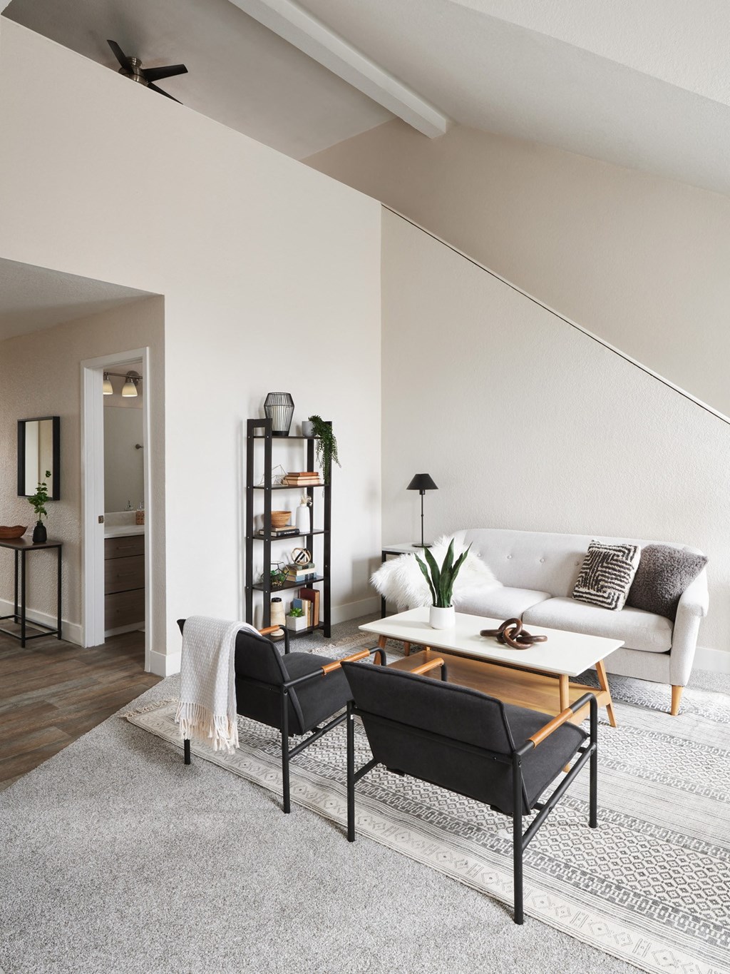 a living room with a white couch and two black chairs