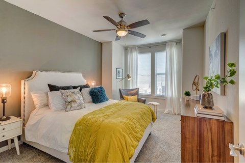 A bedroom with a white bed and a yellow comforter.