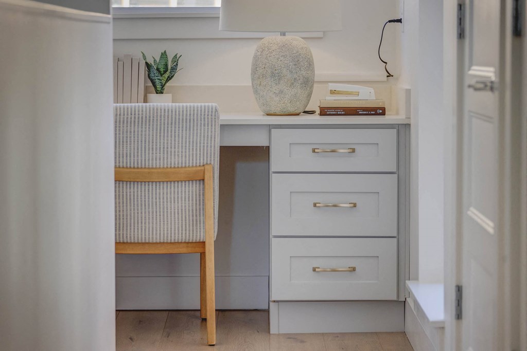 a desk with drawers and a chair in a small room