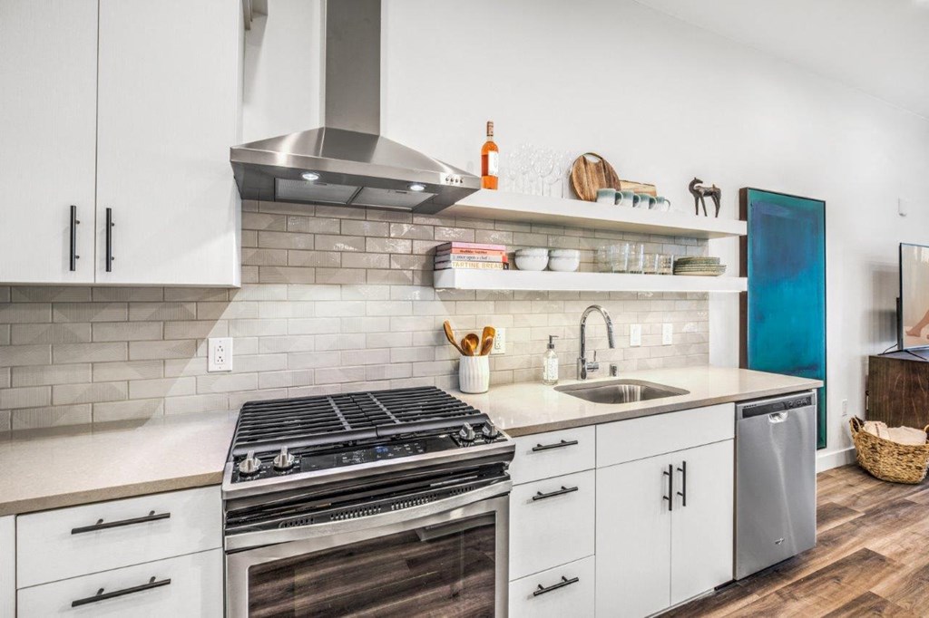 a kitchen with white cabinets and a stainless steel stove top oven
