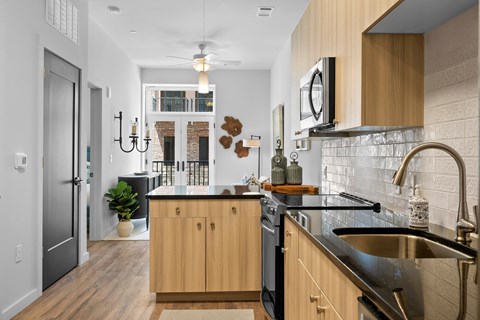 A kitchen with wooden cabinets and a black fridge.