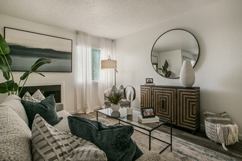 A living room with a grey couch and a green pillow.