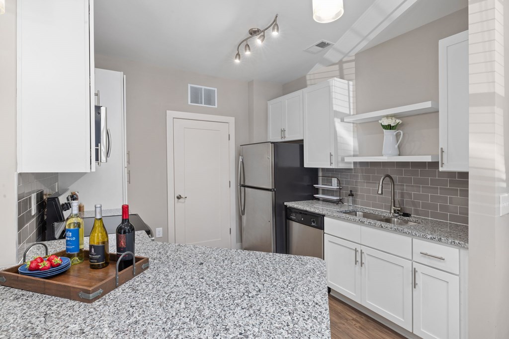 A kitchen with a tray of food and wine bottles on the counter.