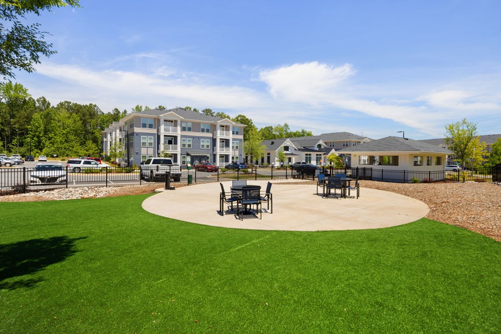 A large grassy area with a circular concrete center and benches.