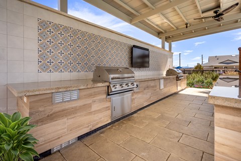A patio with a built-in grill and a tiled wall.