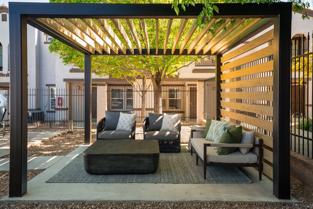 A Patio With Couches and Chairs Under a Wooden Pergola at Cantata at the Trails, New Mexico, 87114