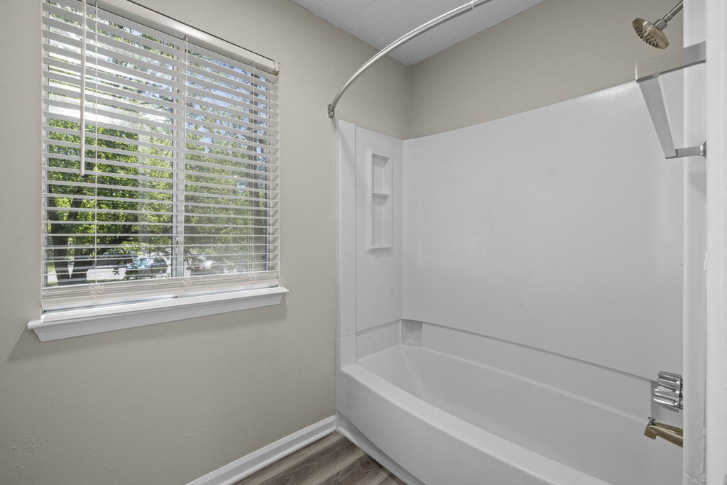 a white bathroom with a window and a shower and a tub