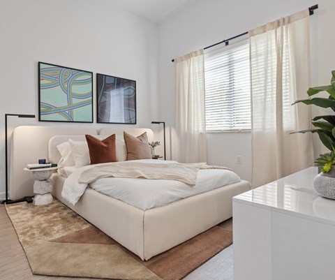 A bedroom with a large bed and two framed pictures on the wall.