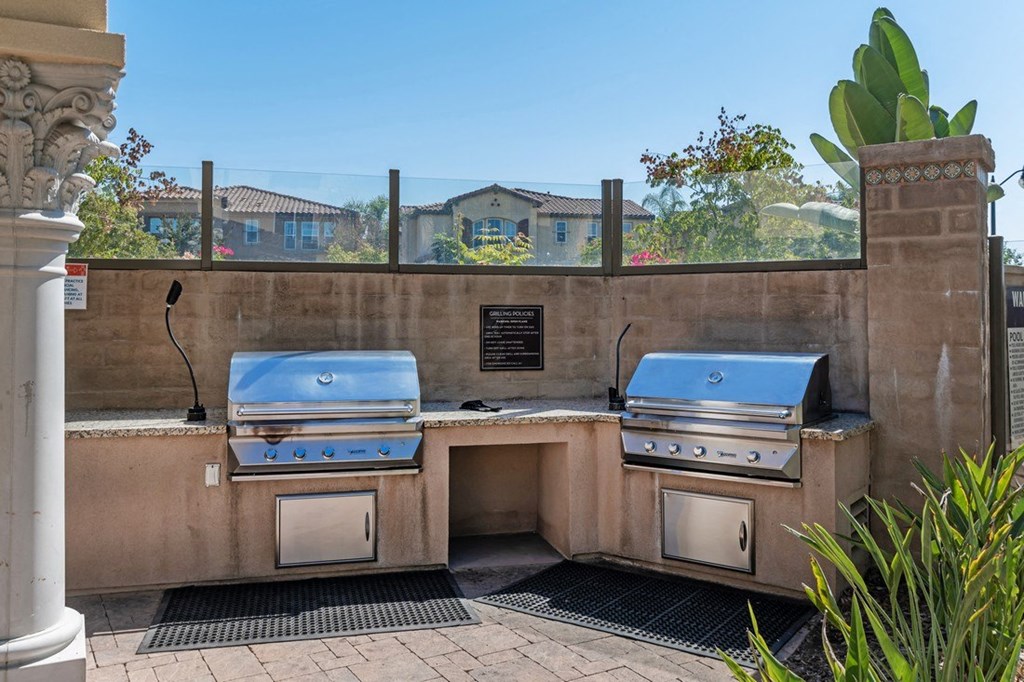A stone wall with two built-in BBQ grills and a plaque on it.