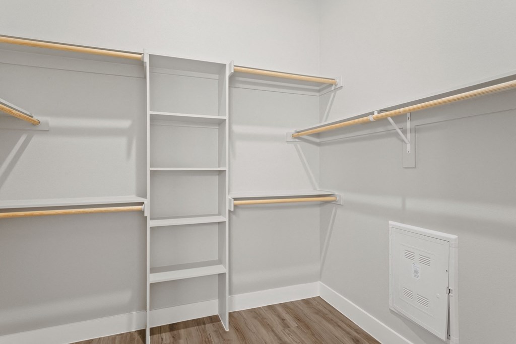 a walk in closet with empty shelves and a door