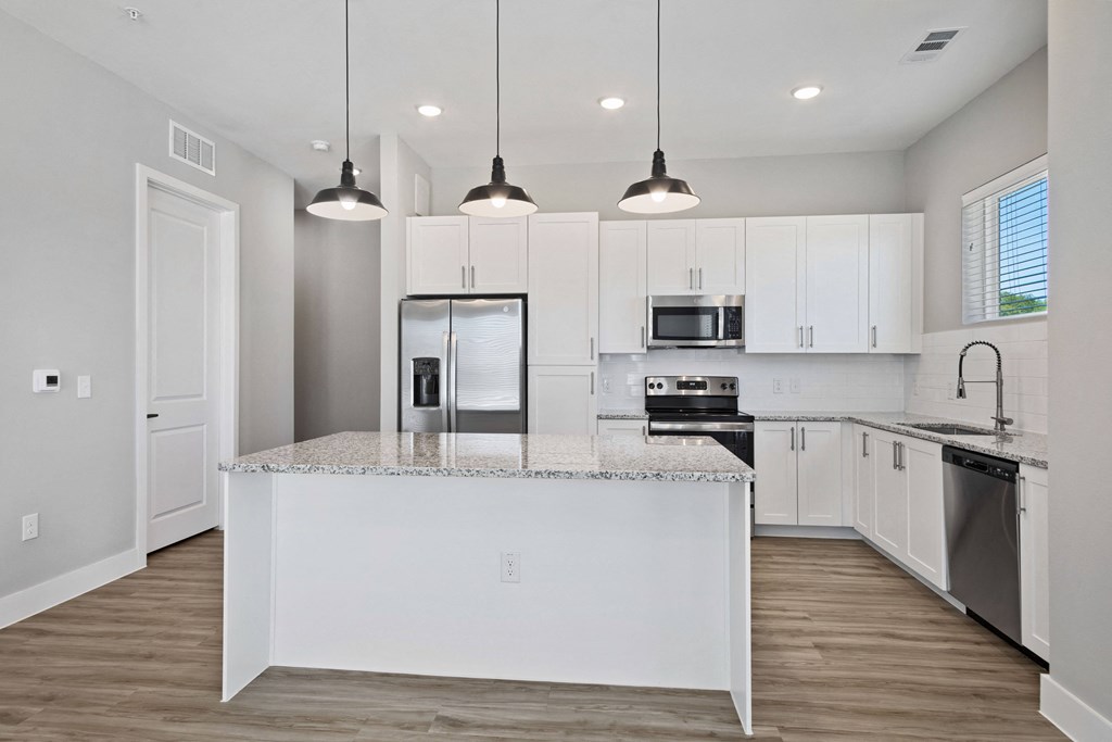 a kitchen with white cabinetry and a large island with a granite countertop