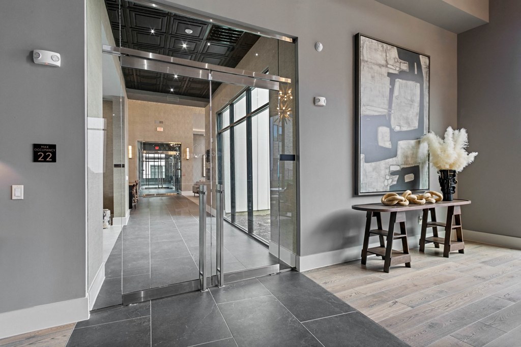 a lobby with glass doors and a table with a vase of flowers