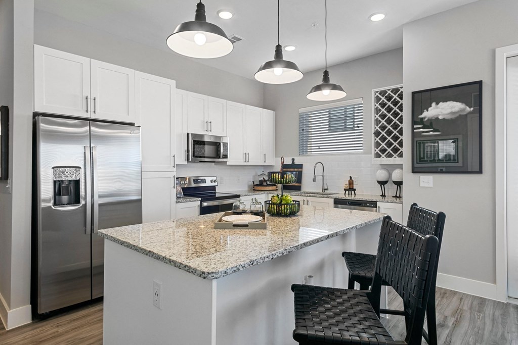 a kitchen with a marble counter top and a stainless steel refrigerator