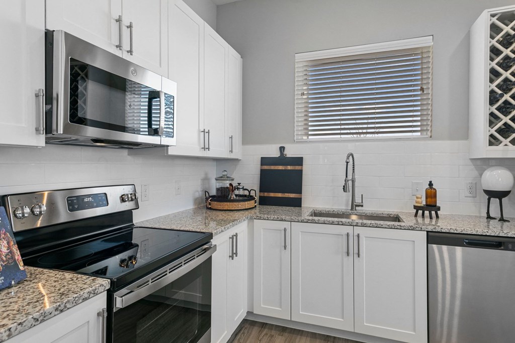 a kitchen with white cabinets and black appliances and granite counter tops
