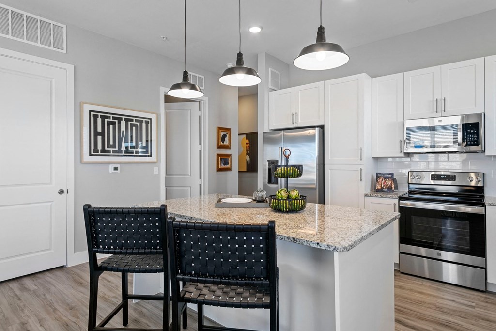 a kitchen with white cabinets and a marble counter top