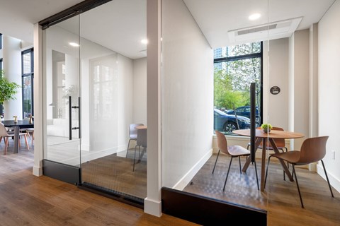 A private work booth featuring a table and chairs with glass walls.