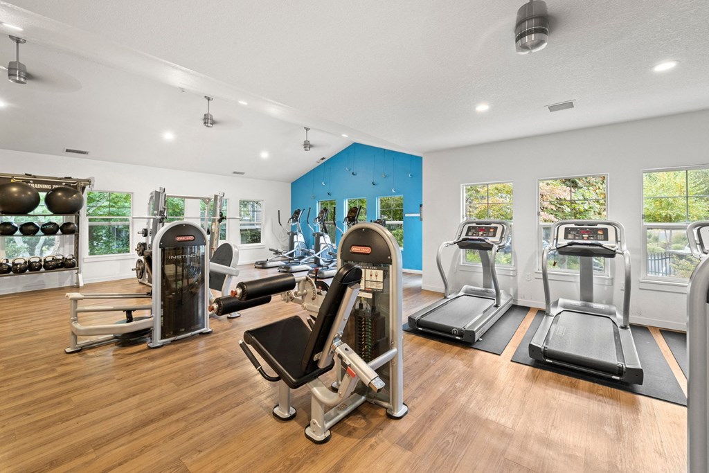 the gym with treadmills and other exercise equipment on a wooden floor