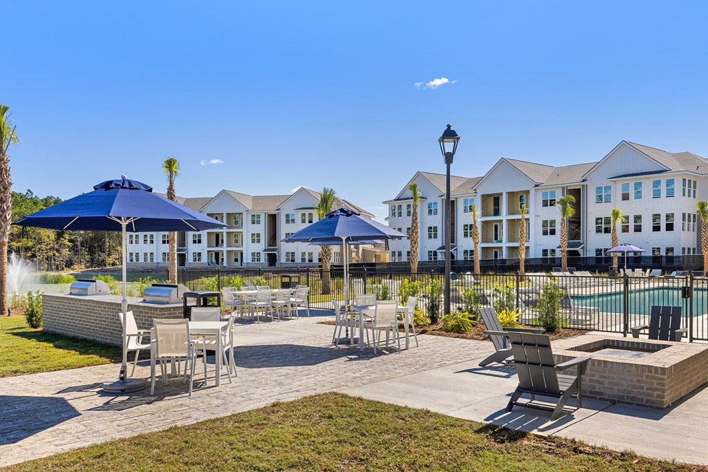 a patio with tables and chairs and umbrellas in front of an apartment building