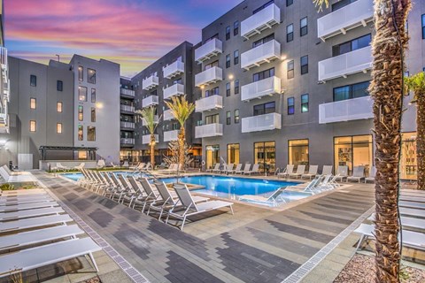 an apartment complex with a swimming pool and chaise lounge chairs