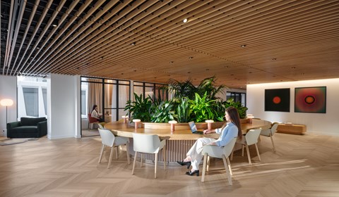 A woman is sitting at a table in a room with wooden floors and ceilings.