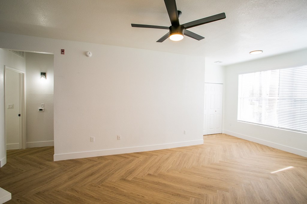 A room with a ceiling fan and wooden flooring.