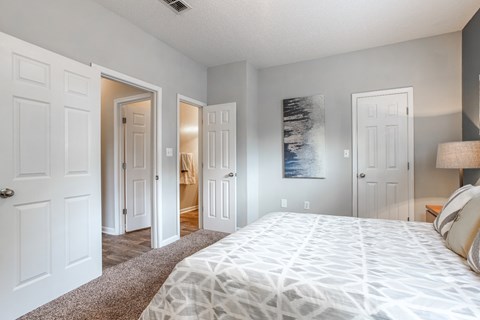A bedroom with a large bed and a painting on the wall.