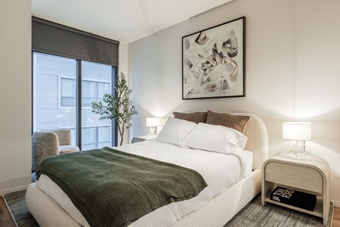 A bedroom with a large bed and a painting on the wall.