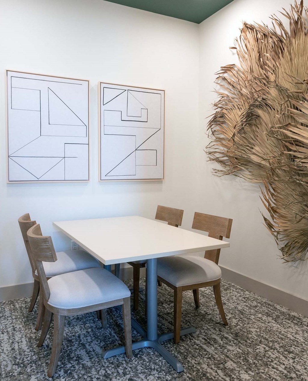 a dining area with a table and chairs and two paintings on the wall