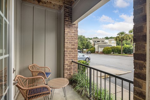 A balcony with a table and chairs overlooking a street.