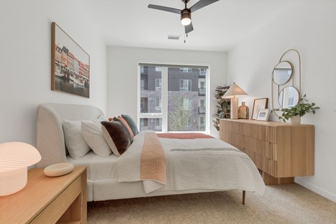A bedroom with a bed, a nightstand, and a window.
