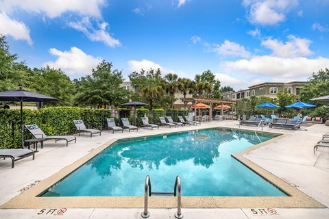 A large swimming pool surrounded by lounge chairs and umbrellas.