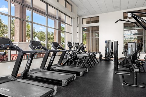 a gym with cardio equipment and windows in a building
