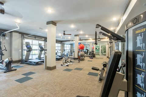 A gym with a variety of equipment including treadmills, weights, and exercise machines.