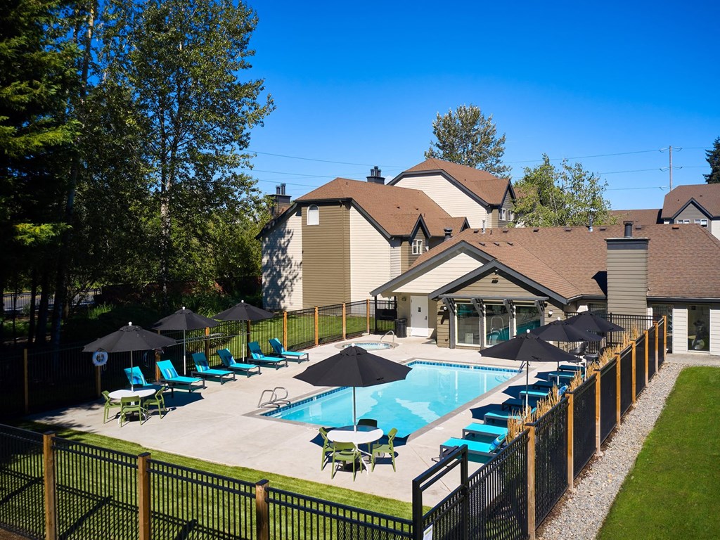 a swimming pool with lounge chairs and umbrellas in front of a house