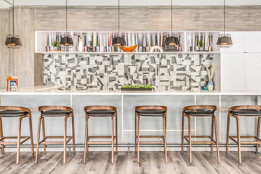 resident lounge kitchen with a white counter top and a row of stools in front of it