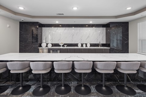 Conference room with a long white tables, chairs, and a kitchen area in the back.