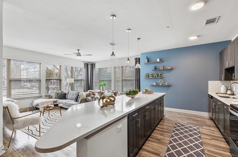 A modern kitchen with a white island and a dining area with a white chair.