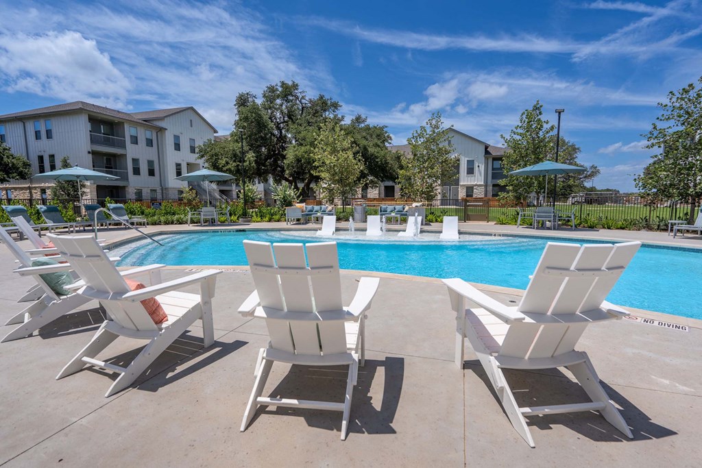 a swimming pool with white lounge chairs and umbrellas