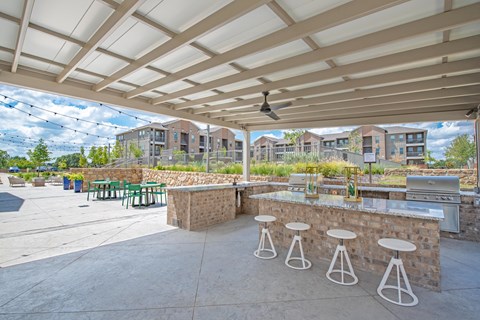 an outdoor patio with a bar and tables with stools