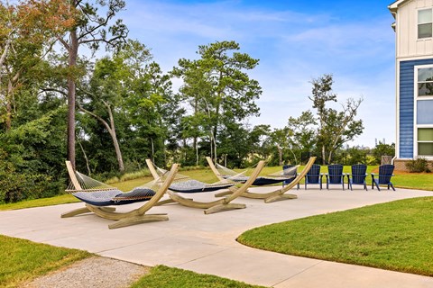 A set of four wooden lounge chairs are arranged on a concrete patio.