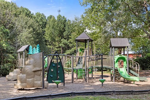 A playground with a green slide and a brown structure.