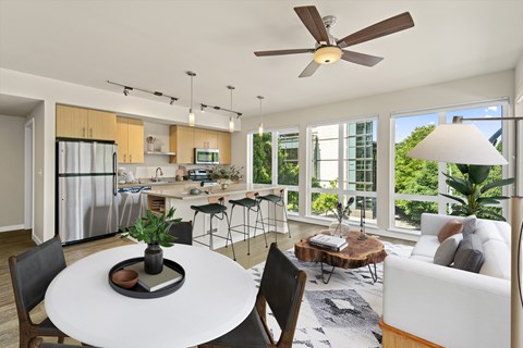 a living room and kitchen with a white table and a ceiling fan
