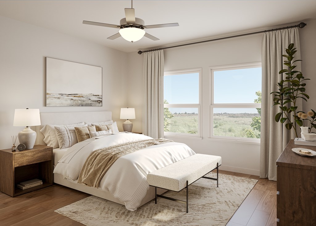 A bedroom with a large bed, a ceiling fan, and a view of the outdoors through the windows.