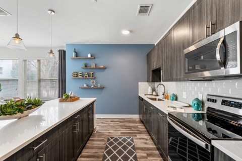 A modern kitchen with a blue accent wall and stainless steel appliances.