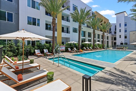 Swimming pool with lounge chairs and umbrellas in front of apartment building at Array La Mesa, La Mesa, CA