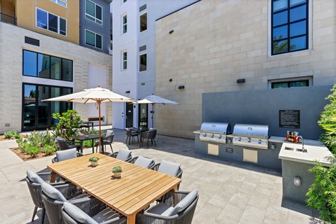 Patio with a wood table and chairs and a grill with two bbq grills at Array La Mesa, California