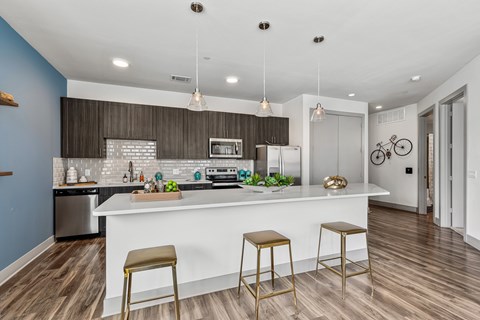 A kitchen with a white counter and bar stools.